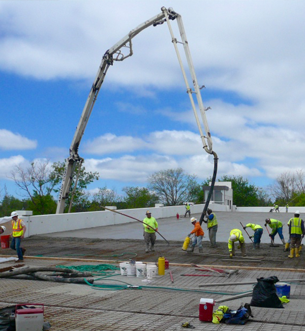 Photo of a workers pouring concrete on the rooftop